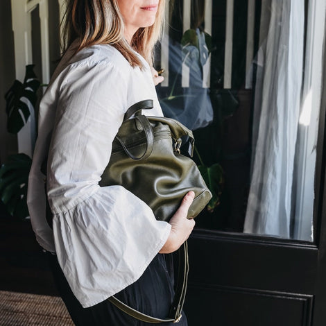 Woman looking out open door with Army Rome Leather Tote under arm showing how supple the leather is.